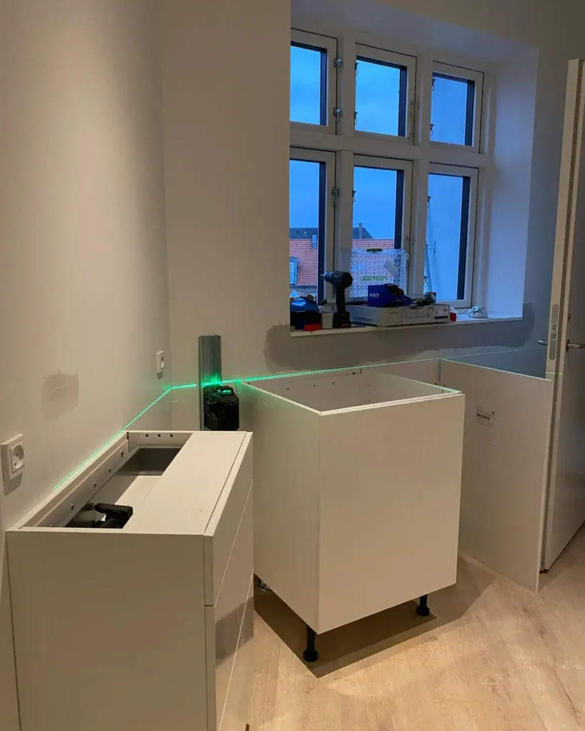 Moderniseret køkken med nyt skab og stort vindue under renovering.