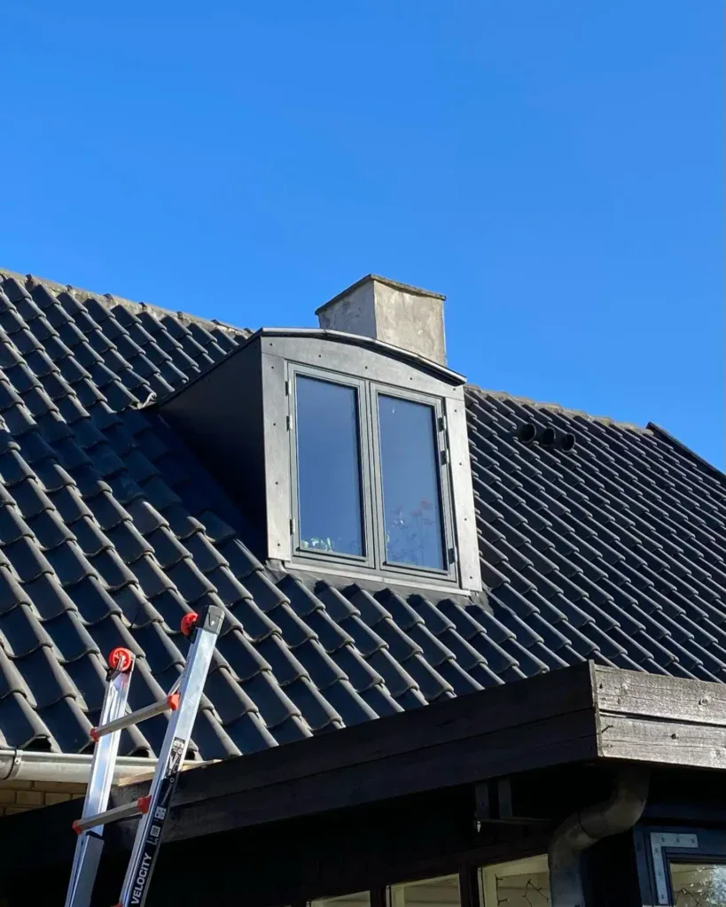 Ny kviste installeret på tag med tagrender under klar blå himmel.