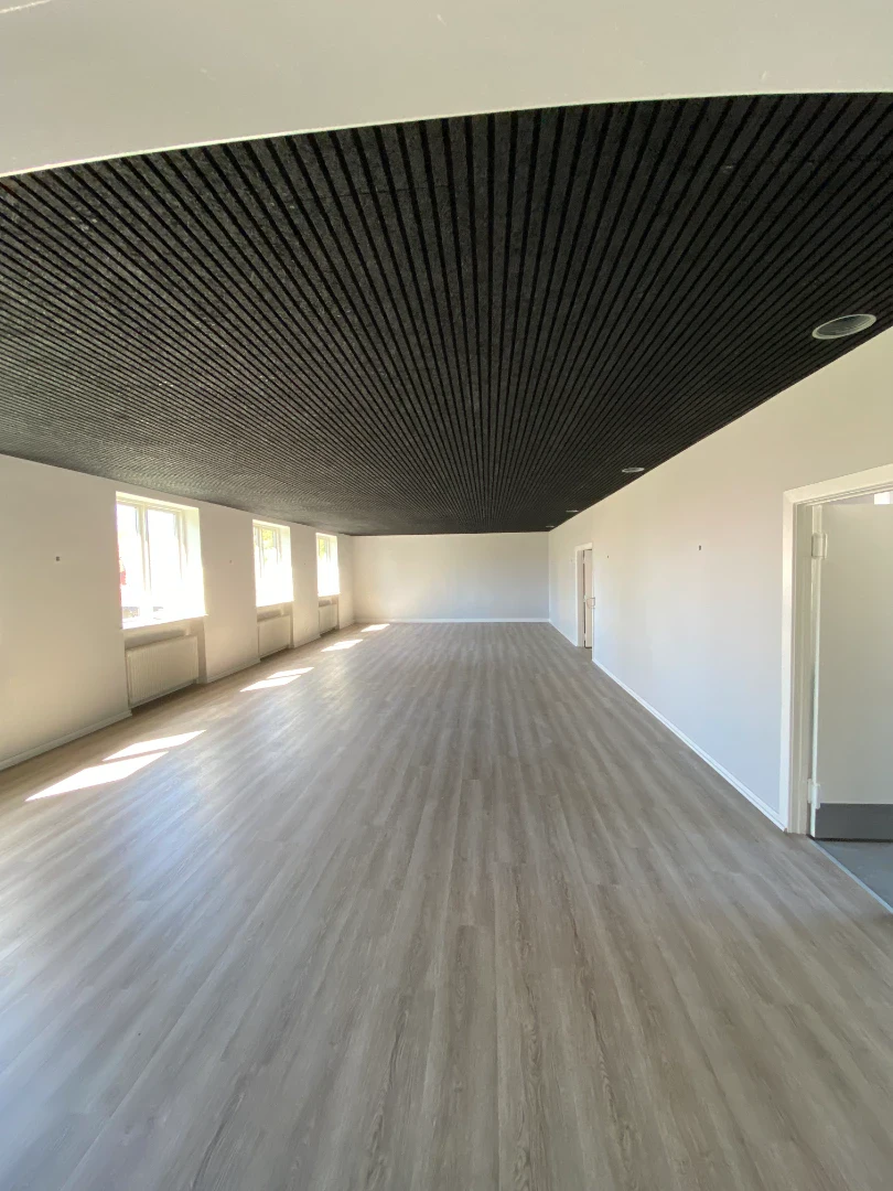 Elegant loft med sort træpanel og lys vægdekoration i et nyrenoveret rum.