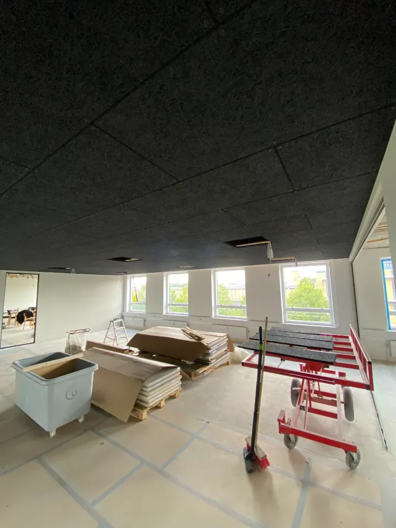 Indendørs byggeplads med tømrerarbejde og materialer klar til installation.